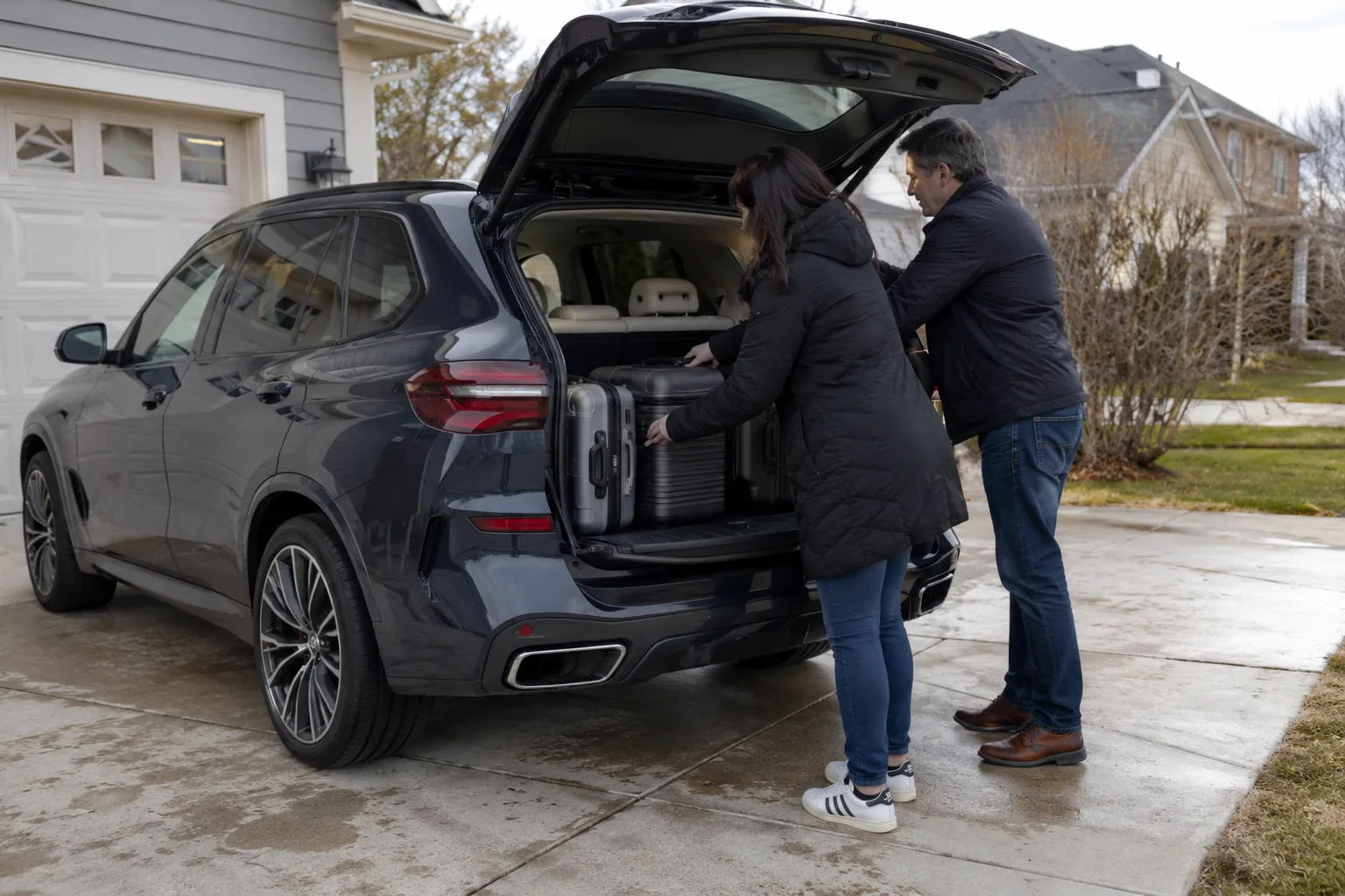 Family loading suitcases into the cargo area of a BMW X5